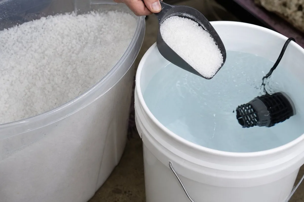 A container of Red Sea Coral Pro Salt being mixed into RO/DI water with a powerhead for circulation